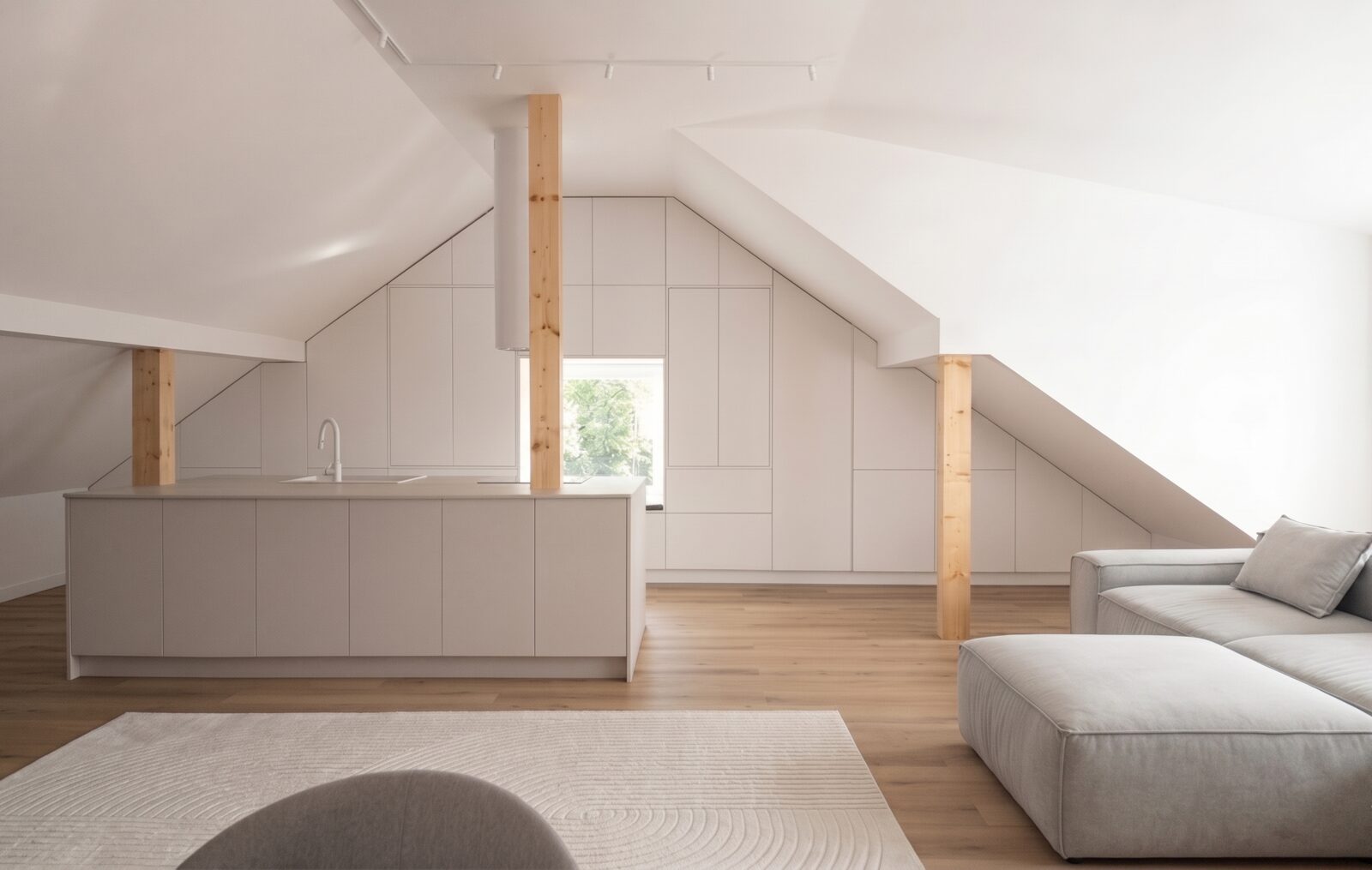 A pale-stone kitchen island under the attic roof, with white cabinetry built into the slope and an exposed timber post beside it.